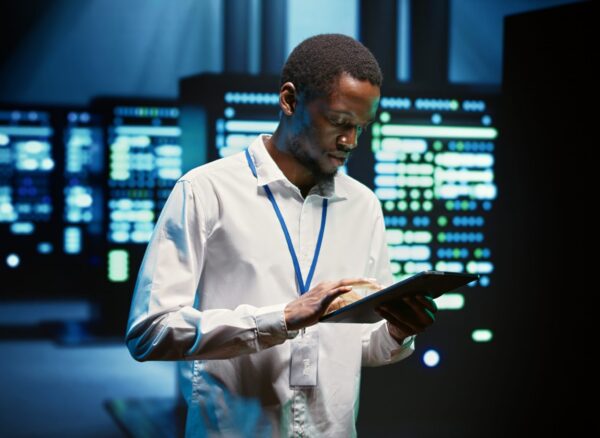 Technician in high tech facility walking through server rigs used for computationally intensive tasks such as molecular modeling or physical simulations. Specialist doing routine equipment maintenance