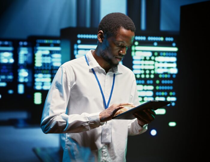 Technician walking through server rigs Technician in high tech facility walking through server rigs used for computationally intensive tasks such as molecular modeling or physical simulations. Specialist doing routine equipment maintenance