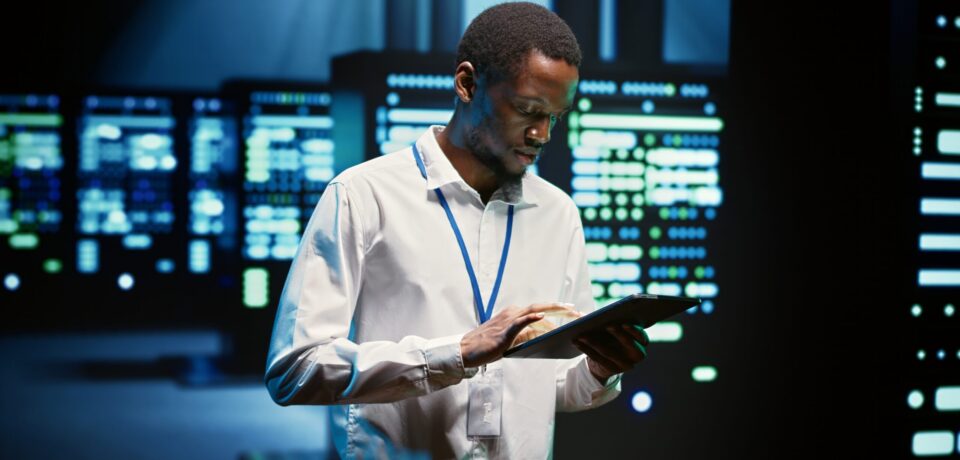 Technician in high tech facility walking through server rigs used for computationally intensive tasks such as molecular modeling or physical simulations. Specialist doing routine equipment maintenance